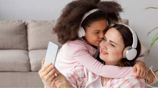 mãe e filha abraçadas ouvindo música com fones de ouvido