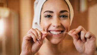 Mulher usando fio dental nos dentes