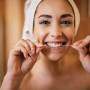 Mulher usando fio dental nos dentes