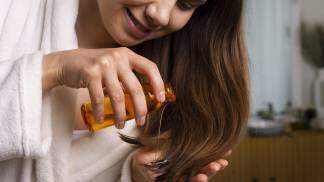Mulher passando óleo no cabelo como cuidado no inverno