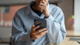Homem pensando e segurando um celular