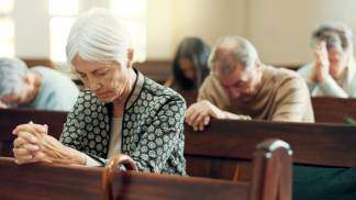 idosos rezando ajoelhados em bancos na igreja 
