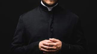 padre com as mãos unidas ao peito 