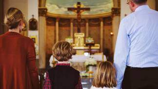 Família de mãos dadas de frente para o altar na igreja 