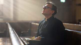 padre rezando sentado no banco da igreja