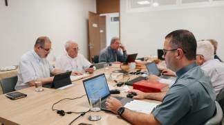 Três pessoas reunidas em uma sala e mexendo no computador
