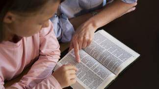 Catequista ensinando a Palavra de Deus para uma criança