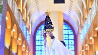 Imagem de Nossa Senhora Aparecida é elevada por um sacerdote no interior do Santuário Nacional, durante celebração religiosa