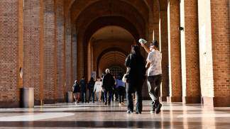 Visitantes caminhando pela arcada com lixeiras posicionadas 